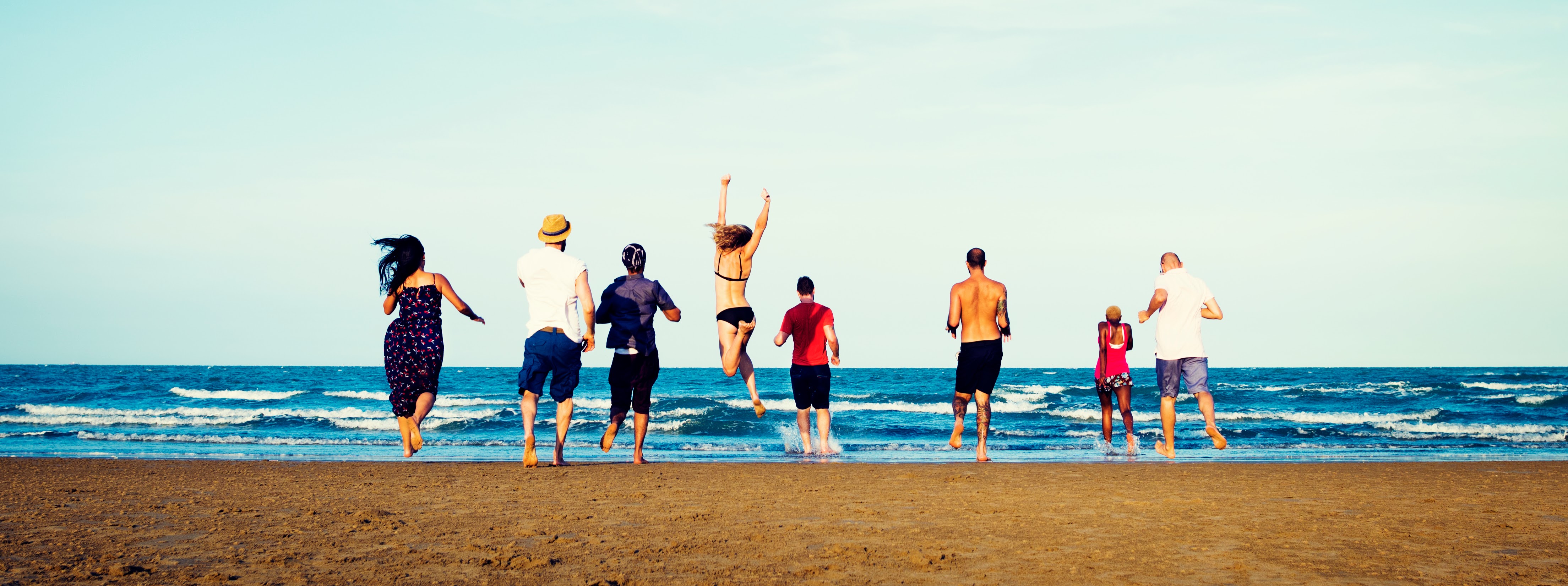 diverse group friends running on beach